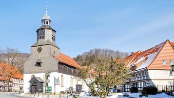 A church with a clock tower, adjacent traditional buildings, and a snow-covered street.