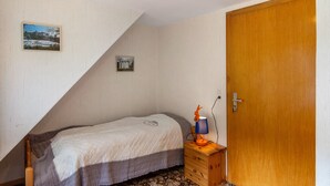 A bedroom with a bed, a wooden dresser, a door, and two framed pictures on the wall. - Holiday Home Adelheid with Unique View, Private Terrace and Wi-Fi (Bad Grund (Harz))