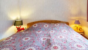 Un dormitorio con una cama, dos lámparas y una figurita de perro rojo.