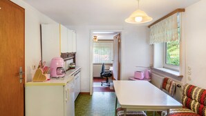 Una cocina compacta con comedor, una ventana con cortinas de encaje y un radiador.