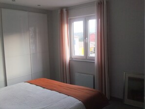 A bedroom with a bed, a wardrobe, a window with curtains, and a radiator. - Modern vacation villa with heated private pool in the most beautiful region of France (Castellane)