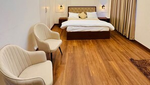 A modern hotel room with a large bed, two bedside tables, a chair, and a wooden floor. - Countryside Heaven Farm (Kharar)