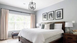 Una camera da letto con un letto grande, comodini, una panca e una finestra con tende.