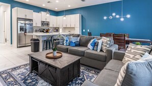 Un salon moderne avec un canapé gris, une table basse en bois et un tapis bleu à motifs.