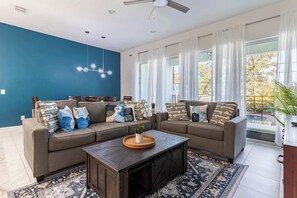 Una sala moderna con un sofá seccional, una mesa de centro de madera y una pared azul decorativa.