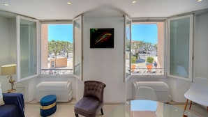 Una habitación moderna con una mesa de vidrio, un sillón tapizado y vistas a la ciudad a través de amplias ventanas.