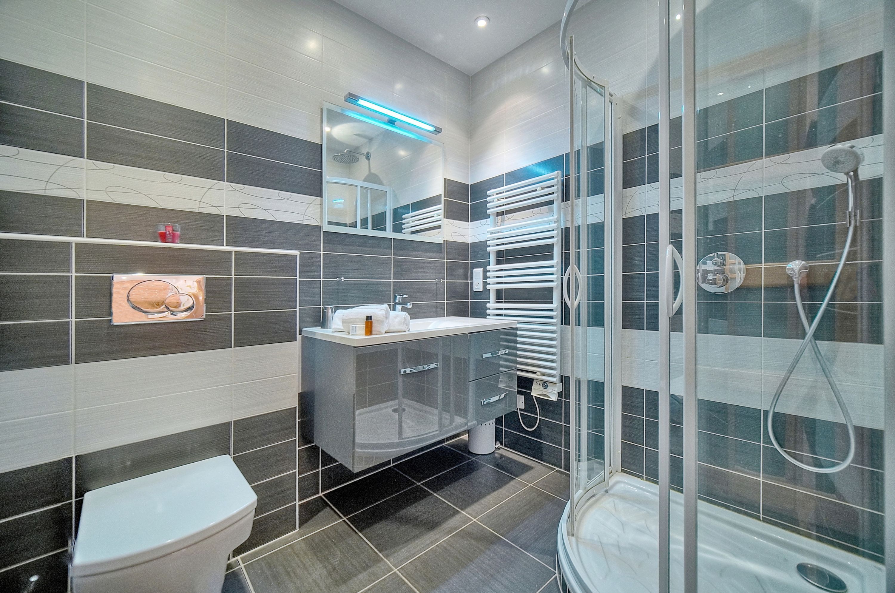 A modern bathroom with a glass-enclosed shower, a vanity with a mirror, and a toilet.