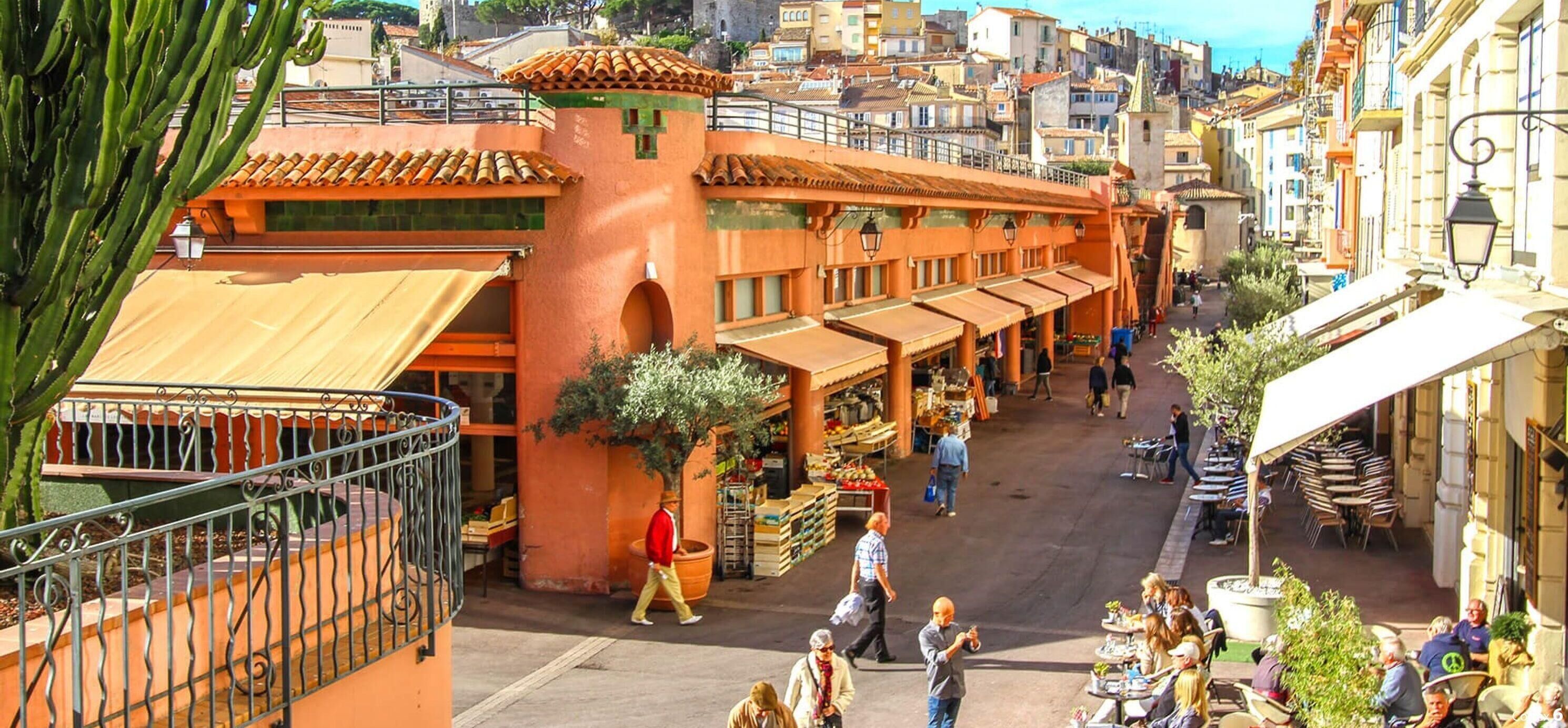 A bustling street with outdoor seating, a market, and a building with a tiled roof.