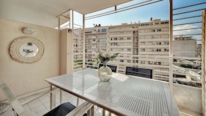 A balcony with a table and chairs, a decorative mirror, and a view of a multi-story building. - Elegant 2 Pieces Piscine Proche Plages A1b235 (Cannes)