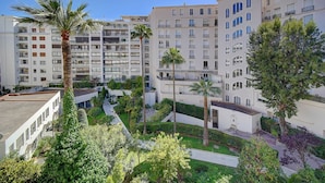 A residential building with multiple balconies, a central courtyard with palm trees, and a mix of modern and traditional architecture. - Studio Moderne Lumineux Proche Croisette A0b132 (Cannes)