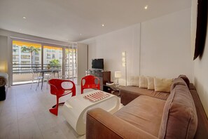 A modern living room with a brown sofa, red chairs, a glass table, and a TV on a stand. - Studio Terrasse 3 min Plage de la Croisettea0b132 (Cannes)