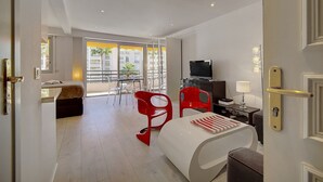 A modern hotel room with a bed, a desk with a computer, a TV, and a balcony with a view of palm trees. - Studio Moderne Lumineux Proche Croisette A0b132 (Cannes)