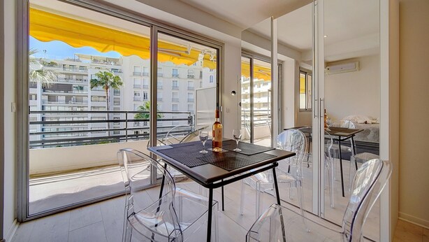 A balcony with a table and chairs, a bottle, and a glass. - Studio Moderne Lumineux Proche Croisette A0b132 (Cannes)
