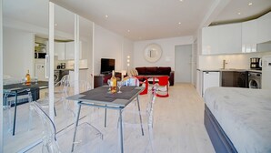 A modern, open-plan living space with a dining area, sofa, and a bed. - Studio Moderne Lumineux Proche Croisette A0b132 (Cannes)