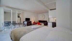 A modern hotel room with a large bed, a desk with a chair, a TV, and a kitchenette. - Studio Moderne Lumineux Proche Croisette A0b132 (Cannes)