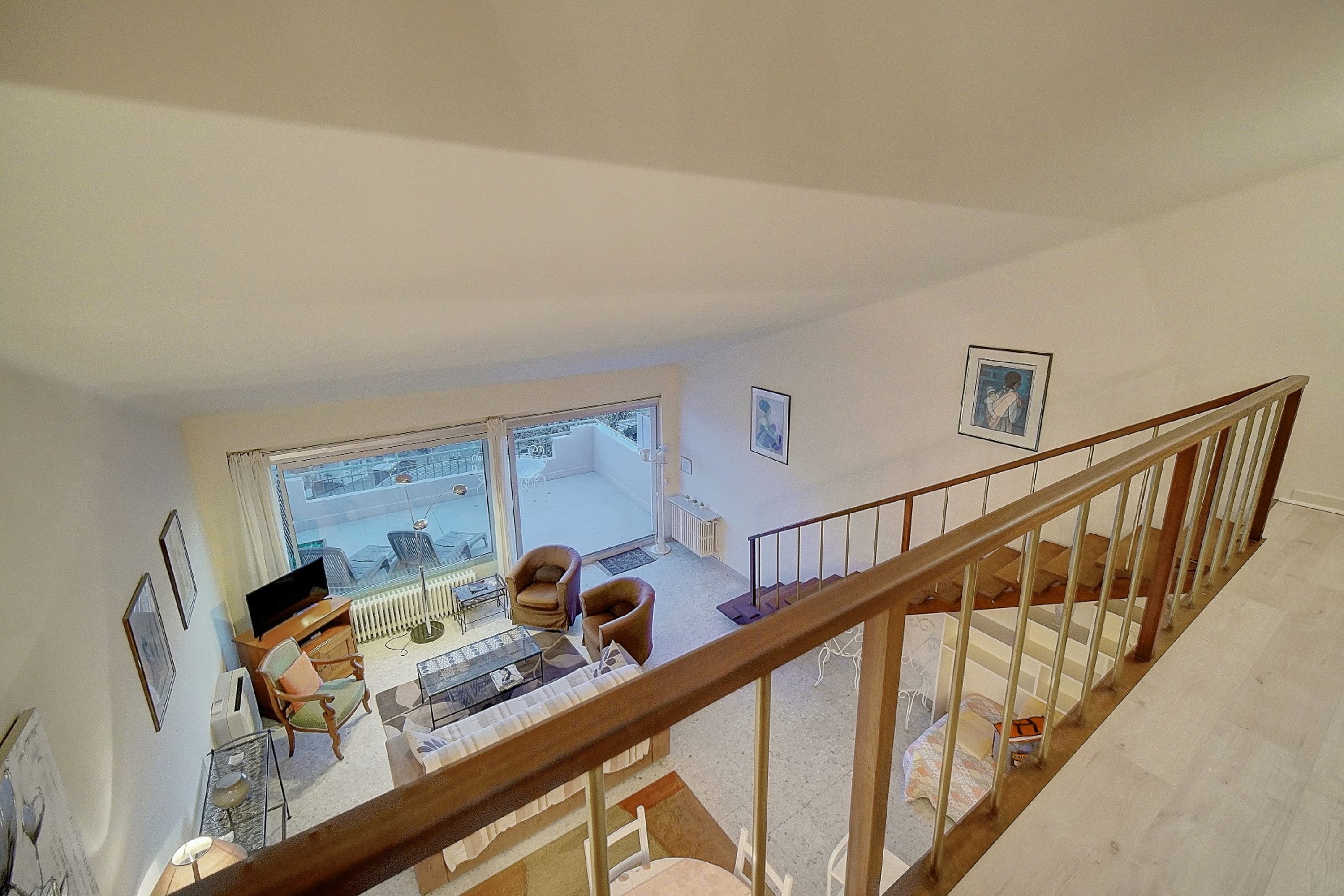 A spacious living area with a large window, a wooden staircase, and a view of the outdoors.