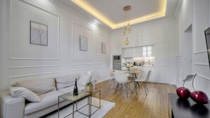 Ein modernes Wohnzimmer mit einem weißen Sofa, einem Couchtisch und einem Essbereich mit kleinem Tisch und Stühlen.