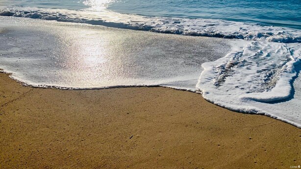 Ein Strand mit sanft anschwellenden Wellen.