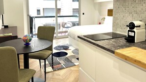 A modern kitchen with a countertop, a coffee maker, and a dining area with a table and chairs. - Studio Moderne 5 MN Plages Croisette A0b191 (Cannes)
