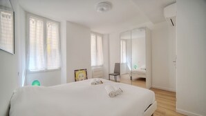 Une chambre d’hôtel moderne, dotée d’un grand lit, d’une chaise, d’un bureau et d’un miroir.