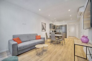 A modern living room with a grey sofa, a dining table with chairs, and a kitchen area in the background. - Charmant 3 pi ces Meynadier A2b243 (Cannes)
