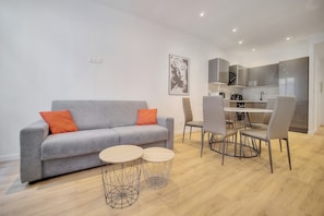 A modern living room with a grey sofa, two round tables, and a dining area with chairs. - Charmant 3 pi ces Meynadier A2b243 (Cannes)
