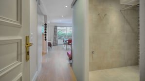 Une chambre d’hôtel moderne dotée d’une douche, d’un coin repas avec une table et des chaises, et offrant une vue sur la verdure environnante.