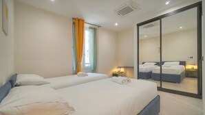 Ein Hotelzimmer mit zwei Betten, einer Glastür und einem kleinen Nachttisch mit Lampe.