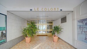 Un pasillo con piso de baldosas, plantas en macetas y un letrero que dice "LE COLONY".