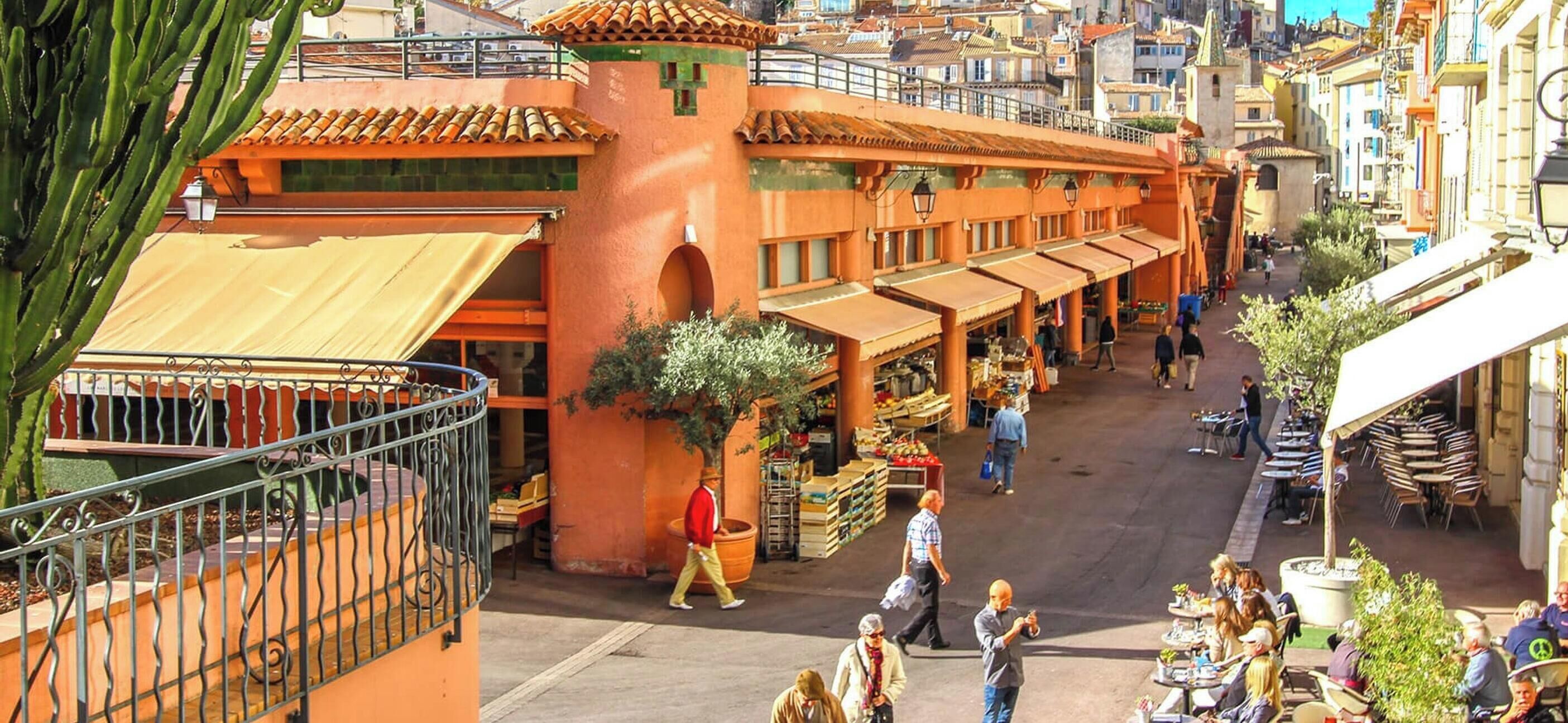 Um mercado de rua movimentado com mesas ao ar livre e diversas lojas.