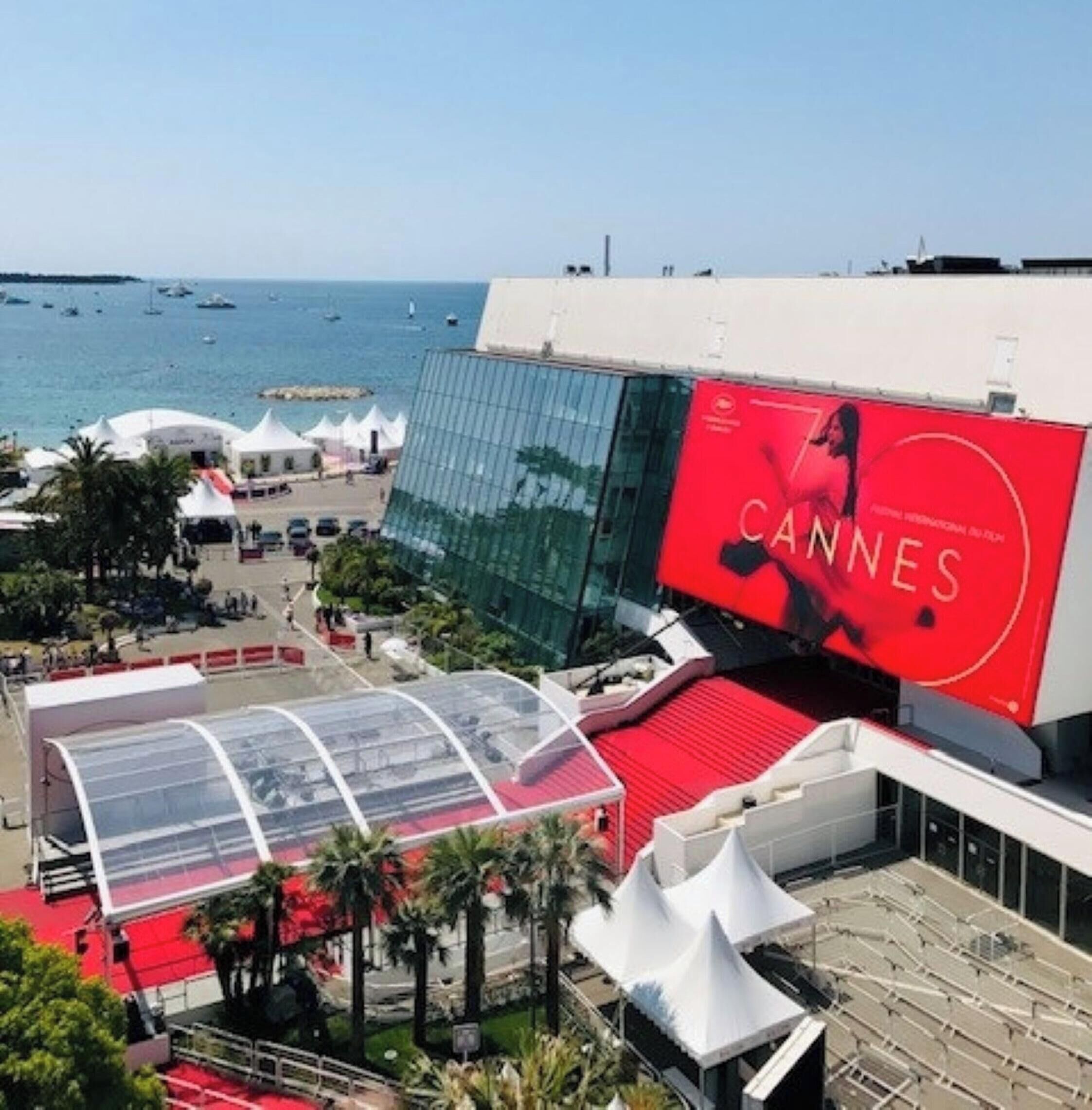 A modern building with a large billboard advertising the Cannes Film Festival.