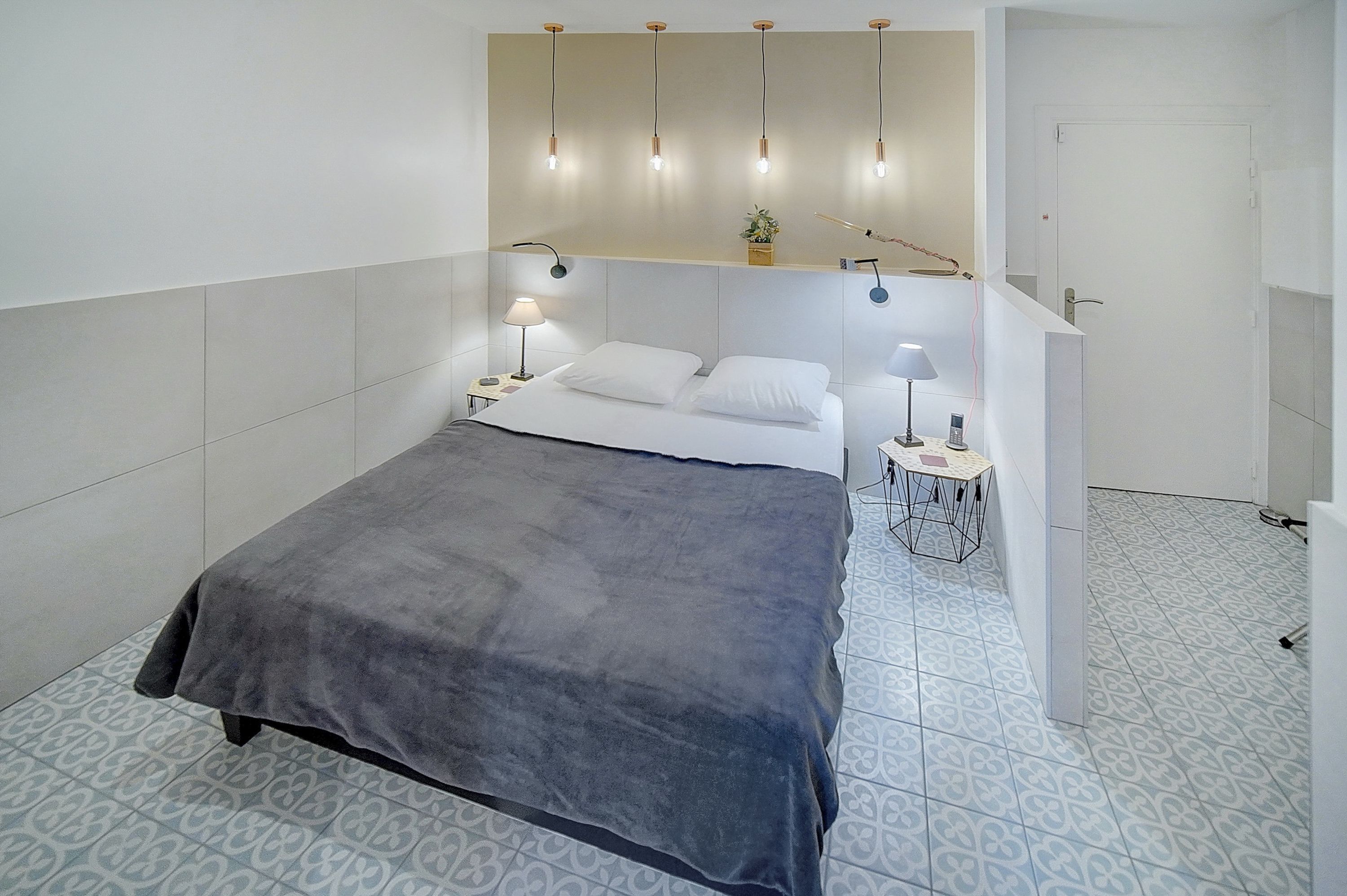 Une chambre moderne avec un lit, des lampes de chevet et une petite table avec une lampe.