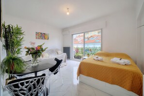 A modern hotel room with a bed, a dining table, chairs, a potted plant, and a window with a view of buildings. - Studio Lumineux 200 m DES Plages A0b192 (Cannes)