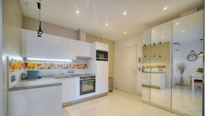 A modern kitchen with white cabinets, a built-in oven, and a microwave. There is a glass partition separating the kitchen from another area. - 2 Pieces Moderne 300 m Plages Croisette A1b238 (Cannes)