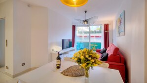 A modern living room with a white table, red sofa, and a TV on a stand. - 2 Pieces Moderne 300 m Plages Croisette A1b238 (Cannes)