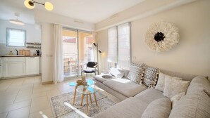 Un salón moderno con un sofá color beige, una mesa de centro de vidrio y un adorno en la pared.