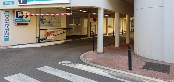 Une entrée de parking avec une barrière, un panneau indiquant « Suquet Forville » et un panneau indiquant « accès interdit ».