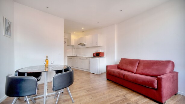A modern living room with a red sofa, a dining table with chairs, and a kitchen in the background. - Charmant 2 Pieces Centre DE Cannes A1b209 (Cannes)