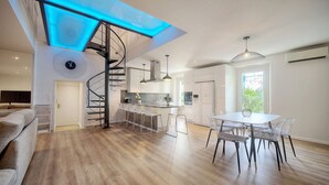 A modern kitchen with a central island, a spiral staircase, and a dining area with a round table and chairs. - Elegant Duplex 5 Chambres Plages DU Midi A5b003 (Cannes)