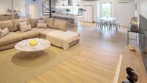 A modern living room with a sectional sofa, a round coffee table, and a dining area with a white table and chairs. - Elegant Duplex 5 Chambres Plages DU Midi A5b003 (Cannes)