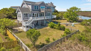 A two-story house with a balcony, a deck, and a view of a lake. - Sounds Right #214-Community pool, private boat dock, kayaks, fish, soundside (North Topsail Beach)