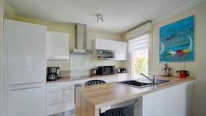 A modern kitchen with white cabinets, a wooden countertop, a microwave, a coffee maker, and a sink. - Beau 3 Chambres Piscine Parking A3b134 (Cannes)