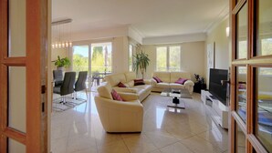 A spacious living room with a sofa set, a coffee table, and a TV. - Beau 3 Chambres Piscine Parking A3b134 (Cannes)