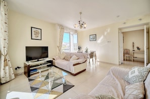 A living room with a flat-screen TV, a sofa, a glass coffee table, and a dining area with a table and chairs. - 3 pi ces Terrasse et Parking A2b237 (Cannes)
