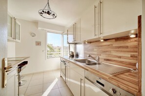 A modern kitchen with a wooden countertop, stainless steel appliances, and a large window providing natural light. - 3 pi ces Terrasse et Parking A2b237 (Cannes)