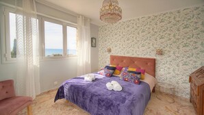 A bedroom with a bed, a chair, a chandelier, and a view of the sea. - 160m2-a C-vue Mer Terrasse Parking A3b132 (Cannes)