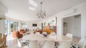 A spacious dining area with a round table, white chairs, and a chandelier. - 160m2-a C-vue Mer Terrasse Parking A3b132 (Cannes)