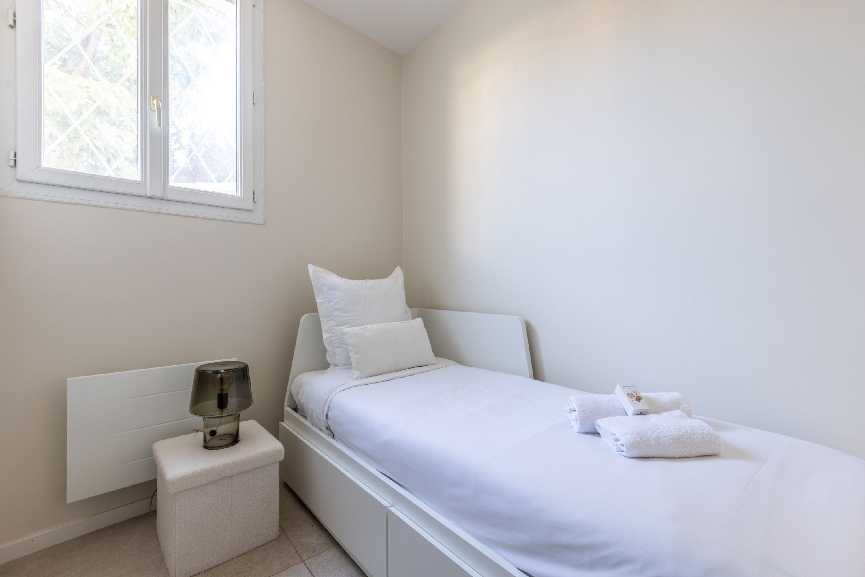 Une chambre à coucher avec un lit, une table de chevet, une lampe et une fenêtre.