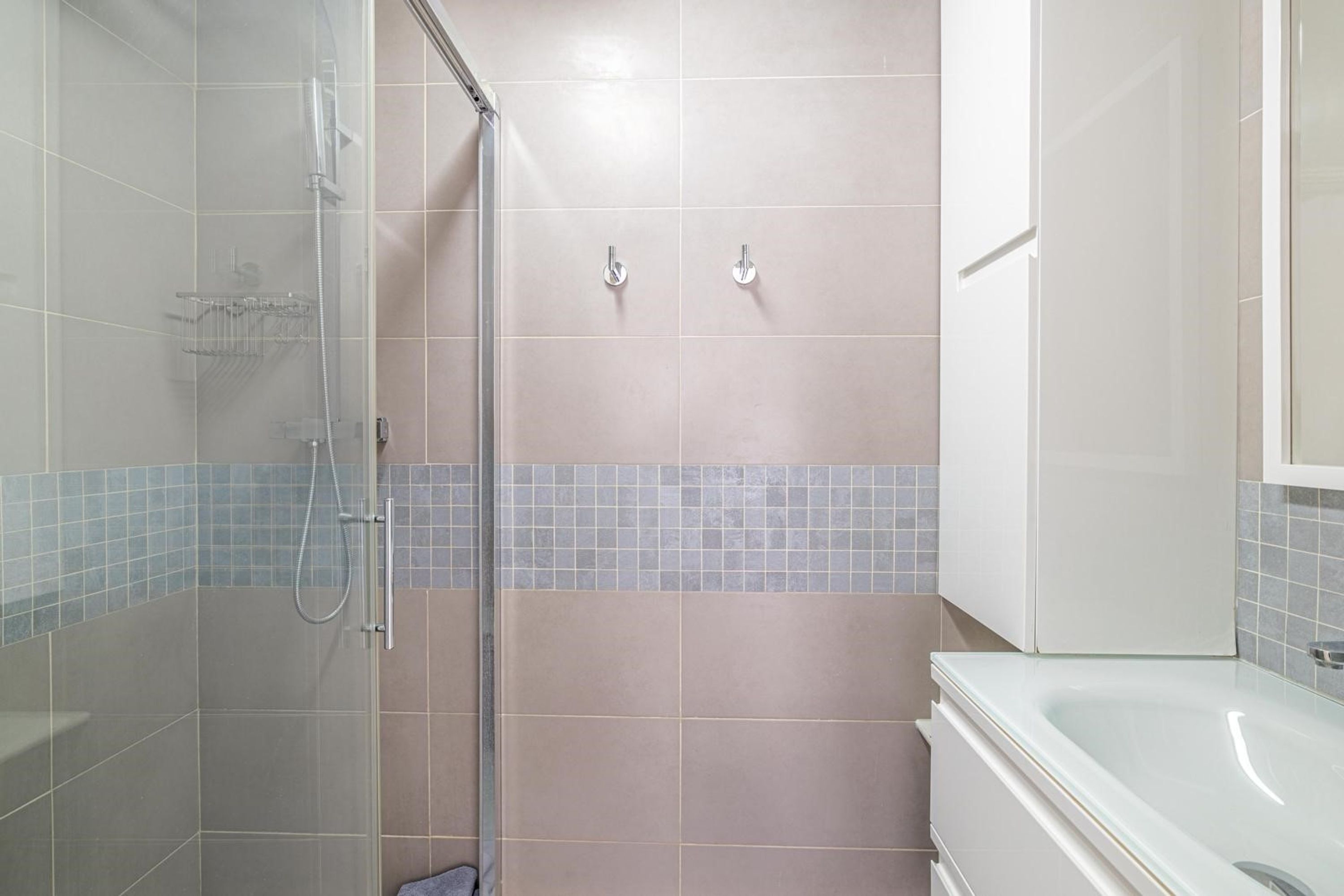 A bathroom with a glass-enclosed shower, a bathtub, and tiled walls.