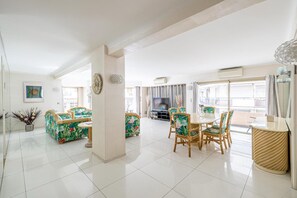 Ein geräumiges Wohnzimmer mit einer Sofagarnitur, einem Esstisch mit Stühlen und einem Fernseher.